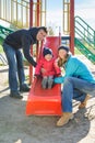 Parents with daughter playing at children`s slide