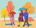 Family walking in the rain with umbrella and wearing raincoats in the city park in autumn season Royalty Free Stock Photo