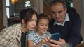 Parents and daughter are viewing photos on the phone at lunch