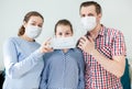 Parents dress medical mask on face of teenage daughter, father and mother wearing facial mask, domestic room