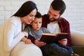 Parents encourage child to read the book while spending time tog
