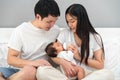 parents (father and mother) feeding milk bottle to newborn baby on bed Royalty Free Stock Photo