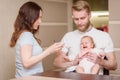 Parents feed their naughty daughter together who refuses to eat fruit puree Royalty Free Stock Photo