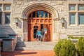 Parents and female student entering large arched doors of University building flanked by metal gothic lamps