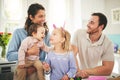 Parents, girl children and bunny ears in family home with funny face, baby or happiness for easter. Man, woman and kids Royalty Free Stock Photo