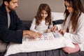 Parents, girl and game of cards in home with bonding, learning and relax with strategy in bedroom. Father, mother and Royalty Free Stock Photo