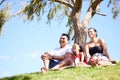 Parents, girl and happy at picnic in park to relax by trees for holiday, bonding and love in nature. Father, mother and Royalty Free Stock Photo