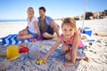 Parents, girl and sandcastle in portrait by sea, blanket and excited with building for holiday in summer. Father, mother Royalty Free Stock Photo