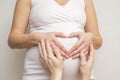 Parents hands making a heart on the belly of the pregnant mother. Pregnant woman and her husband holding her hands in a heart Royalty Free Stock Photo