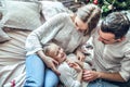 Parents having fun with their little daughter on bed