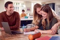 Parents Helping Teenage Daughter With Homework Sitting At Kitchen Table At Home Using Laptop Royalty Free Stock Photo