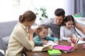 Parents helping their daughters with homework at table Royalty Free Stock Photo