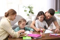 Parents helping their daughters with homework at table Royalty Free Stock Photo