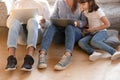 Parents holding laptops sitting on floor with kid holding phone