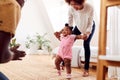 Parents At Home Encouraging Baby Daughter To Take First Steps Royalty Free Stock Photo