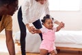 Parents At Home Encouraging Baby Daughter To Take First Steps Royalty Free Stock Photo