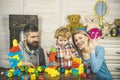 Parents and kid with happy faces make brick constructions. Royalty Free Stock Photo