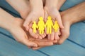 Parents and kid holding cutout of family in hands at turquoise wooden table, top view Royalty Free Stock Photo