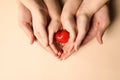 Parents and kid holding red heart in hands on beige background, top view Royalty Free Stock Photo