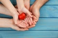 Parents and kid holding red heart in hands at turquoise wooden table, top view. Family day Royalty Free Stock Photo