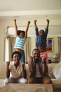 Parents and kids having fun while watching television in living room Royalty Free Stock Photo