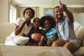 Parents and kids having fun while watching television in living room Royalty Free Stock Photo