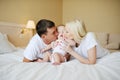 Parents kiss the baby in bed