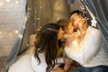 Parents kiss their daughter sitting under a New Year`s garland of lights