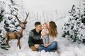 Parents kiss their son and sit on artificial snow in the photo zone for Christmas and new Year in the winter