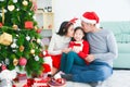 Parents kissing daughter and giving xmas present at living room,decorated by christmas tree Royalty Free Stock Photo