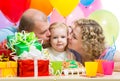 Parents kissing kid girl on birthday party Royalty Free Stock Photo