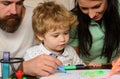 Parents and little child playing together. Cheerful son drawing with father and mother enjoying spending time. Kid Royalty Free Stock Photo