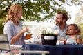 Parents looking each other, smiling, drinking juice with straw, with little girl in dad`s lap Royalty Free Stock Photo