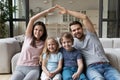 Parents making shape of house roof over head of children