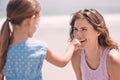 Parents need protection too. a little girl applying suntan lotion to her mothers face at the beach. Royalty Free Stock Photo