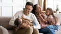 Parents play with daughters sit on couch in living room