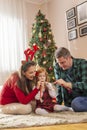 Parents playing with daughter on Christmas day, blowing party whistles Royalty Free Stock Photo