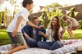 Parents Playing Game With Children On Blanket In Garden