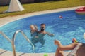 Parents playing with squirt guns with their daughter at the swimming pool Royalty Free Stock Photo