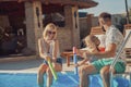 Parents playing with their daughter by the swimming pool, splashing water on each other Royalty Free Stock Photo