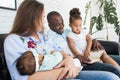 Parents read a book to children sitting on the couch. Happy multiethnic family. Family values