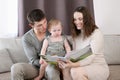 Parents read a book to their child, look at educational pictures, sitting on couch at home.Happy family concept,learning Royalty Free Stock Photo