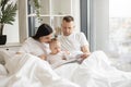 Parents reading baby book with daughter in bed at home Royalty Free Stock Photo