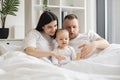 Parents reading baby book with daughter in bed at home Royalty Free Stock Photo