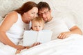 Parents reading book to daughter in bed. place for text on white paper.