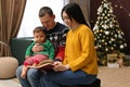 Parents reading book to their cute son in room decorated for Christmas Royalty Free Stock Photo