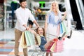 Parents Riding Excited Daughter In Shopping Cart Walking In Mall