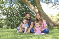 Parents Sitting With Children In Field close to a tree Royalty Free Stock Photo