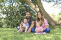 Parents Sitting With Children In Field close to a tree Royalty Free Stock Photo