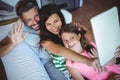 Parents sitting on sofa with daughter and clicking a selfie on digital tablet